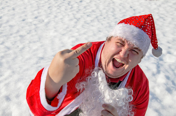 Hombre gordo divertido vestido como Santa Claus está sentado en la nieve
 - Foto, imagen