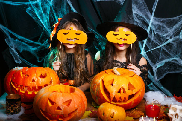 Мама и ее дочь в костюмах ведьм веселятся дома. Счастливая семья готовится к Хэллоуину
. - Фото, изображение
