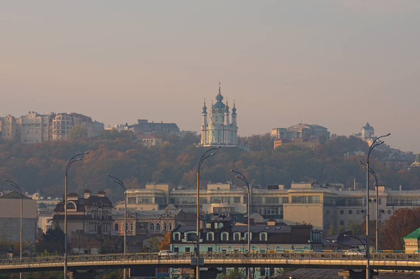 Picturesque view of St. Andrew's Church at the hill and one of the oldest district in Kyiv Podil during autumn sunrise. Landscape of Kyiv (Kiev), Ukraine  - Photo, Image
