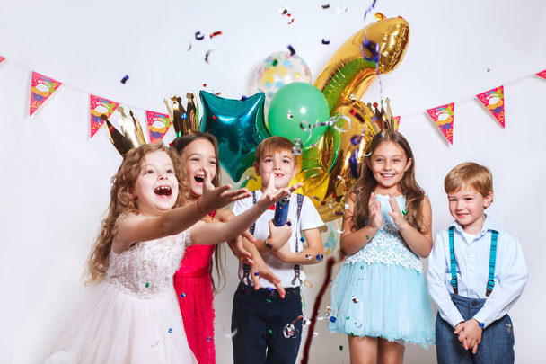 Party fun. Group of beautiful kids throwing colorful confetti and looking happy on birthday party - Valokuva, kuva