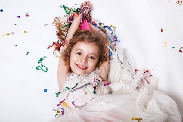 Funny happy girl celebrating birthday party, smiling and lying in multicolored confetti - Фото, зображення