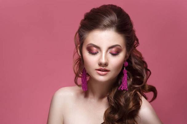 Fashion beauty portrait of a beautiful girl with a bright make-up and an elegant hairdress on a pink background. - Foto, afbeelding