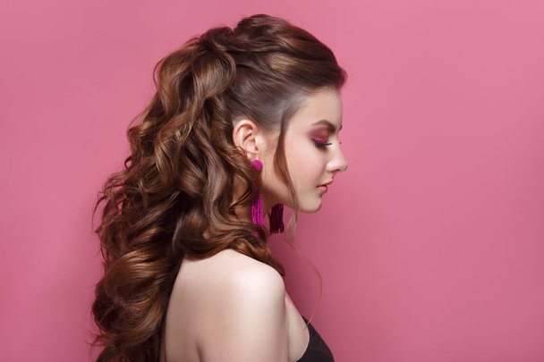 Fashion beauty portrait of a beautiful girl with a bright make-up and an elegant hairdress on a pink background. - Foto, Bild