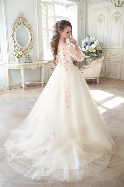An elegant woman in a long light dress with embroidery in a chic interior. - Photo, Image
