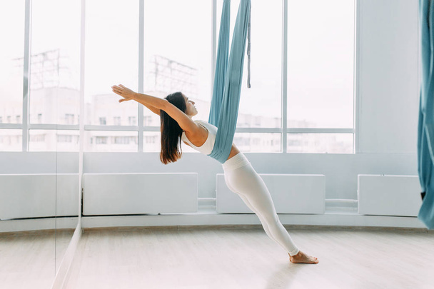 Training on a hammock with a beautiful girl. Yoga in the gym. Stretch marks sitting, lying and standing. - Φωτογραφία, εικόνα