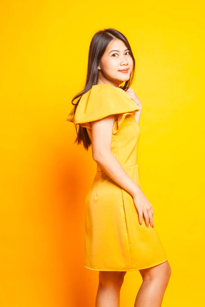Beautiful young Asian woman in yellow dress on yellow background - Photo, image