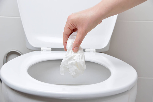 hand of a person who drop tissue paper in the toilet bowl - Фото, зображення