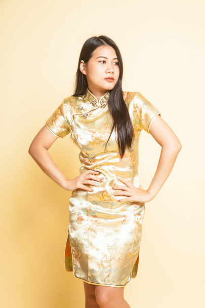Asian girl in golden chinese cheongsam dress  on beige background - Φωτογραφία, εικόνα