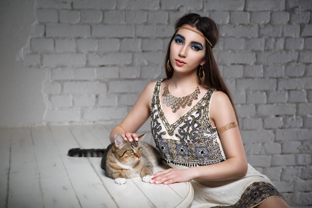 Beautiful girl in the image of Egyptian Cleopatra with a cat. - Valokuva, kuva