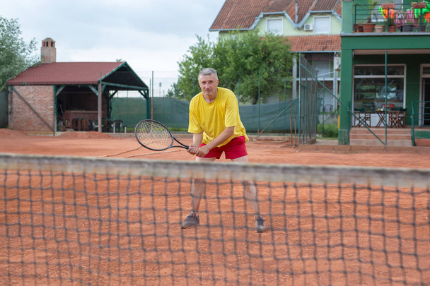 Μεγαλύτερος άντρας παίζει τένις αναψυχής για διασκέδαση εκτός - Φωτογραφία, εικόνα