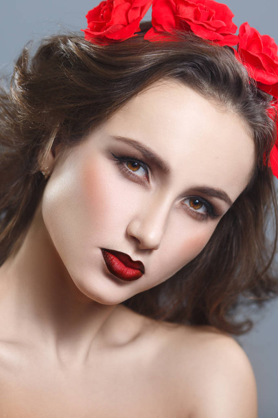 Beauty portrait of a beautiful woman with red lipstick and a decorative wreath on a gray background. - Foto, imagen