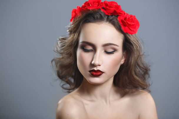 Beauty portrait of a beautiful woman with red lipstick and a decorative wreath on a gray background. - Foto, Imagem