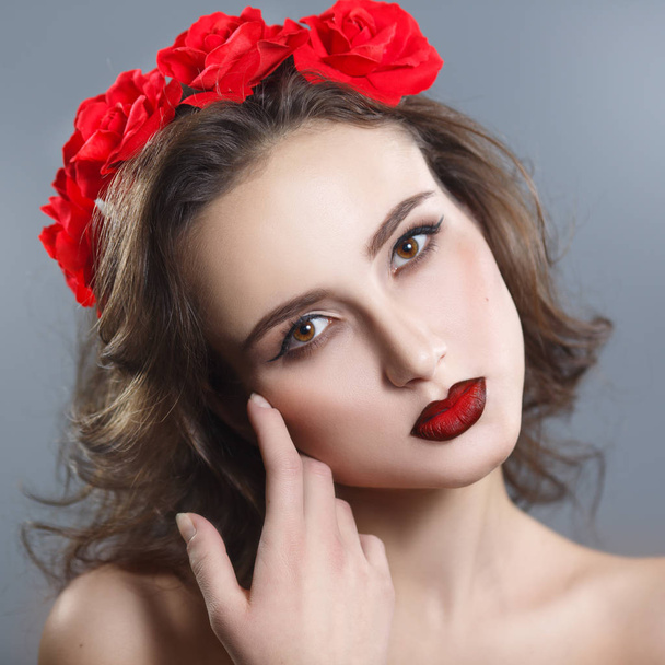 Beauty portrait of a beautiful woman with red lipstick and a decorative wreath on a gray background. - Fotografie, Obrázek