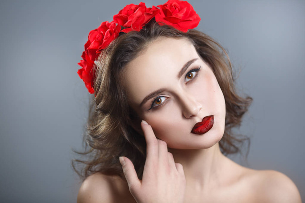 Beauty portrait of a beautiful woman with red lipstick and a decorative wreath on a gray background. - Photo, image