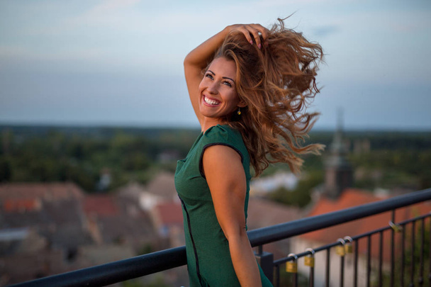 Beautiful young woman playing with her hair while smiling outside - Foto, Imagen