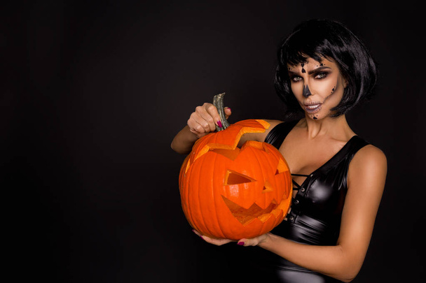 Sexy brunette woman in Halloween makeup and lingerie hold a pumpkin on a black background in the studio. Make-up skeleton, monster and witch - Zdjęcie, obraz