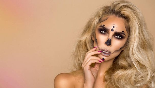 Sexy blondynka w Halloween makijaż na beżowym tle w studio. Szkielet artysty makijaż, monster, czarownica. - Zdjęcie, obraz
