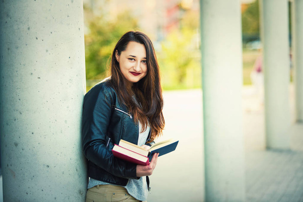 Νεαρή γυναίκα φοιτητής Αναζήτηση σελίδων βιβλίου στο σπάσιμο μεταξύ μαθήματα κολέγιο. Εκπαιδευτική έννοια, έξυπνο κορίτσι ψάχνει για φωτογραφική μηχανή. - Φωτογραφία, εικόνα