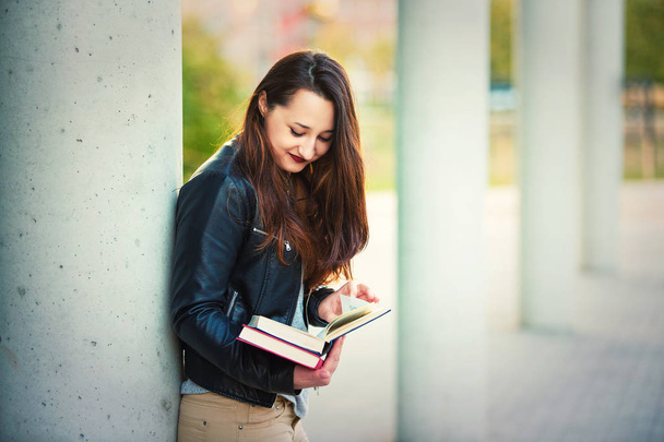 Νεαρή γυναίκα φοιτητής Αναζήτηση σελίδων βιβλίου στο σπάσιμο μεταξύ μαθήματα κολέγιο. Εκπαιδευτική έννοια, έξυπνο κορίτσι ανάγνωση. - Φωτογραφία, εικόνα