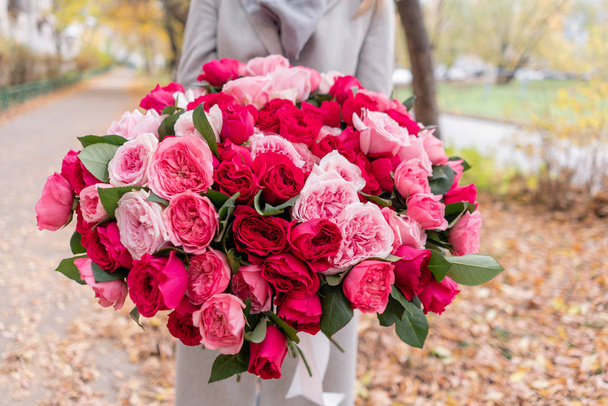 Nagy luxus világos csokor a kezében egy aranyos lány. Száz kerti rózsák, David Austin fajták. Háromféle világos rózsaszín, scarlet és pasztell színek. Ősz a parkban. - Fotó, kép