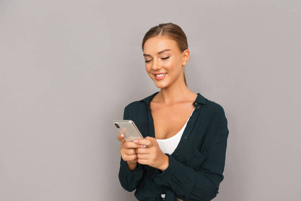 Image of cheerful happy business young woman posing isolated over grey wall background using mobile phone. - Fotoğraf, Görsel