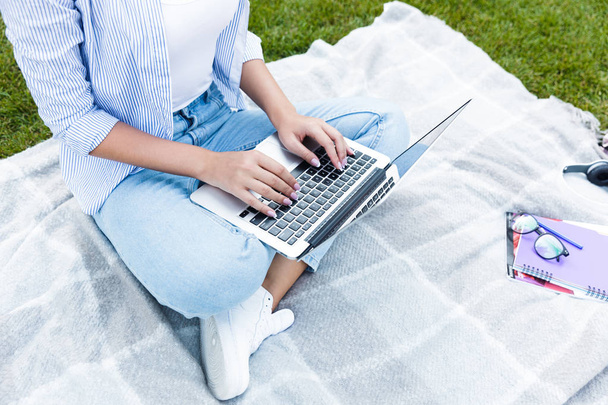 Bijgesneden foto van jonge vrouw in park buitenshuis gebruik van laptopcomputer. - Foto, afbeelding