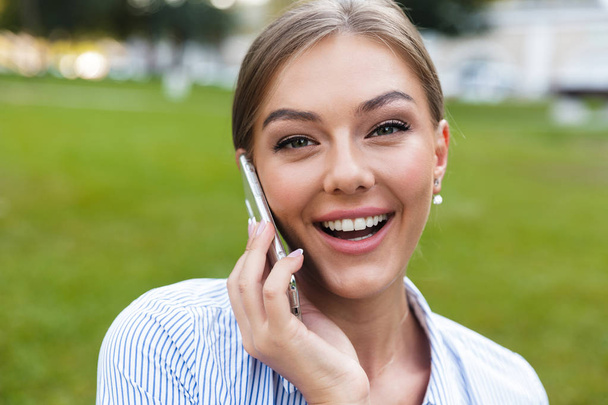 Close up of cheerful young girl talking on mobile phone outdoors - Φωτογραφία, εικόνα