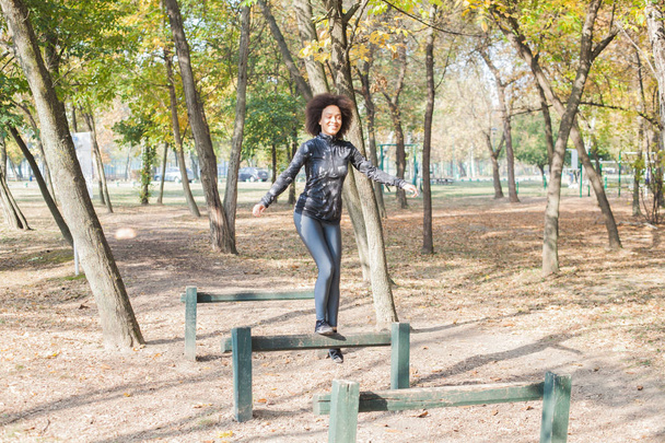 African Woman Training In Forest At Morning In Autumn Park, Running And Jumping Over Hurdles. - Photo, Image