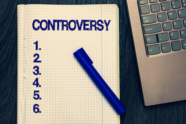 Text sign showing Controversy. Conceptual photo Disagreement or Argument about something important to showing Open notebook squared page black marker computer keyboard wooden background. - Photo, Image
