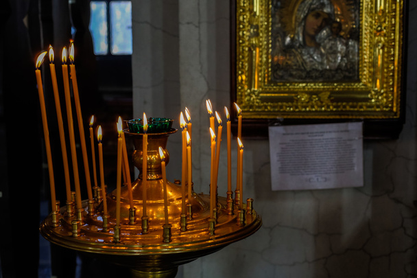 Intérieur de l'église orthodoxe russe. Bougies sous l'ancienne icône encadrée de l'or
. - Photo, image