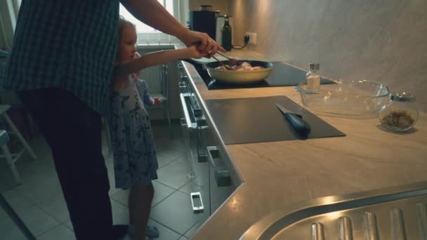 Батько у плетеній сорочці готує курячі палички для своїх дітей на здоровий обід на домашній кухні
 - Кадри, відео