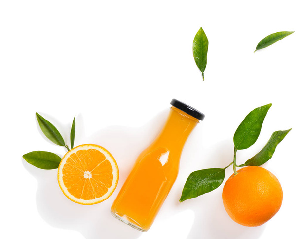 Top view of orange juice in a glass bottle, whole orange and orange slice with green leaves isolated on white background. - Foto, afbeelding