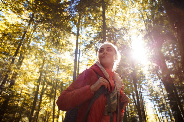 happy smiling woman in a red jacket walks in the autumn forest - Fotó, kép