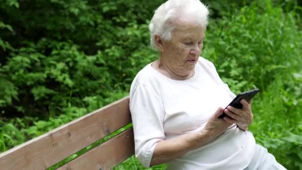 stará babička se dívá na internetu smartphone - Záběry, video