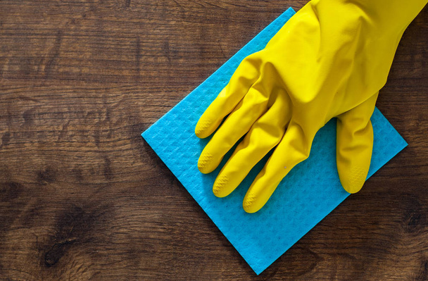 Hand in a glove with a rag cleans wooden floor panels. Cleaning the house. - Fotó, kép