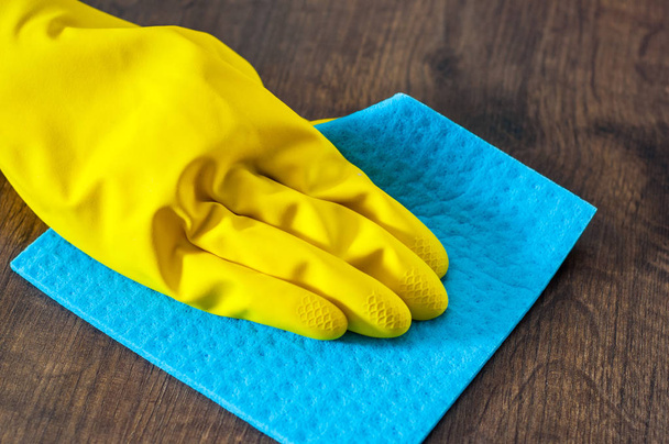 Hand in a glove with a rag cleans wooden floor panels. Cleaning the house. - Фото, зображення