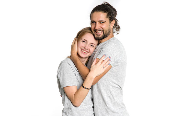 Portrét šťastnému páru na bílém pozadí. Pár muž a žena objímala a při pohledu na fotoaparát. - Fotografie, Obrázek