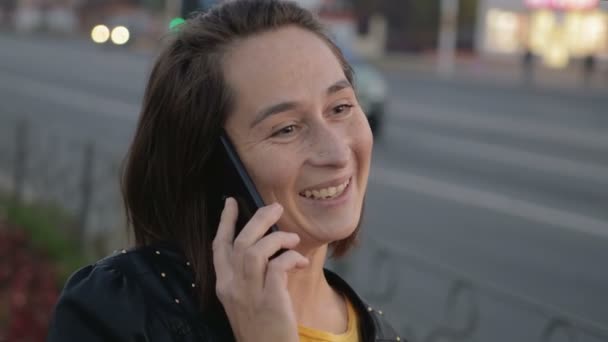Şehir gürültüsünden, bokeh arka plan üzerinde bir cep telefonu konuşurken genç kız - Video, Çekim