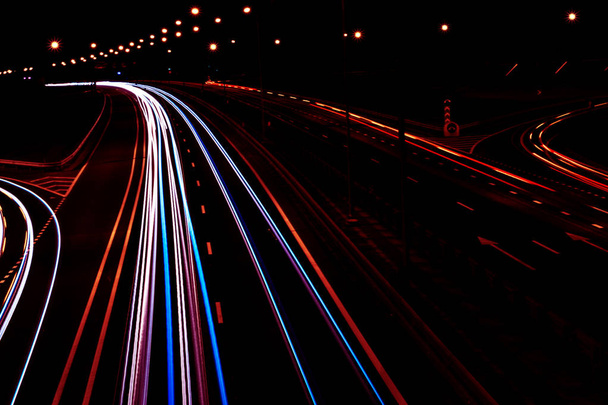 Cars light trails on a curved highway at night. Night traffic trails. Motion blur. Night city road with traffic headlight motion. Cityscape. Light up road by vehicle motion blur. - Foto, Imagem