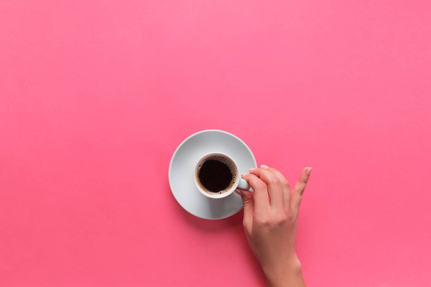 Alto ângulo de mãos de mulher segurando xícara de café no fundo rosa Estilo minimalista. Flat lay, vista superior isolada
. - Foto, Imagem