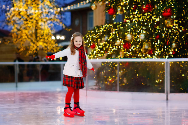 Gyerek Jégkorcsolya park télen jégpálya. Gyermekek karácsonyi vásár korcsolya. Kis lány korcsolyát a hideg nap. Kültéri móka a hóban a gyermek. Téli sportok. Karácsonyi családi vakáció a gyerek. - Fotó, kép