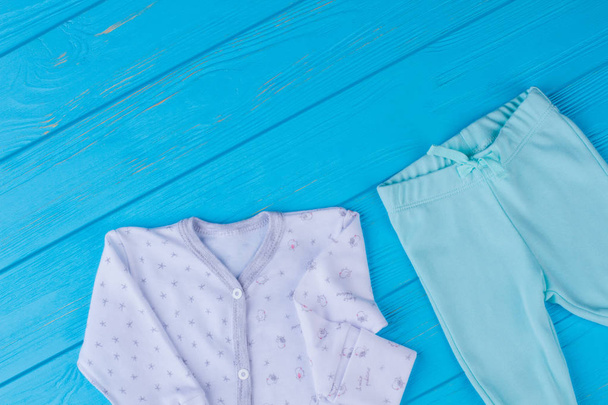Ropa de bebé ropa de dormir en madera azul. Pantalones de bebé pijama y azul suave bebé
. - Foto, imagen