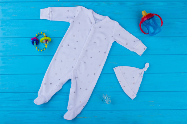 Conjunto de roupas de dormir para bebês, brinquedos e acessórios. Vista superior. Fundo de madeira azul
. - Foto, Imagem