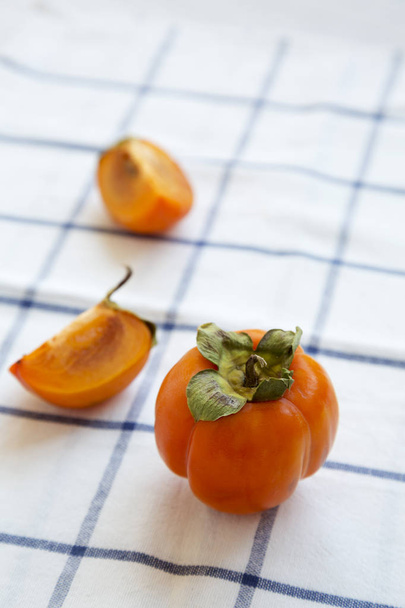 Fresh persimmon on cloth, side view. Close-up. - Фото, изображение