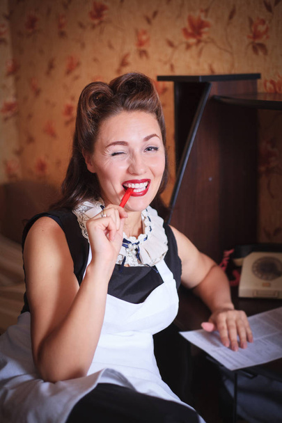 Krásná usměvavá žena sedí u stolu a podepisování dokumentu. Retro styl, vintage. - Fotografie, Obrázek