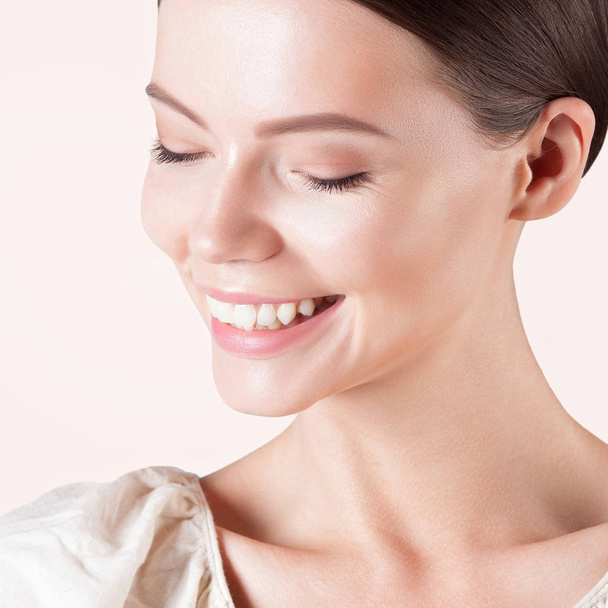 Νεαρή γυναίκα χαμογελαστή με γκρο πλαν καθαρό τέλειο δέρμα. Πορτραίτο της ομορφιάς - Φωτογραφία, εικόνα
