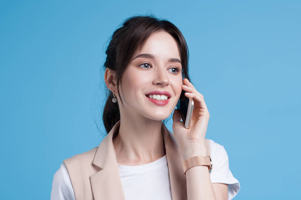 Beautiful successful young business woman uses phone on blue background. Business portrait - Fotografie, Obrázek
