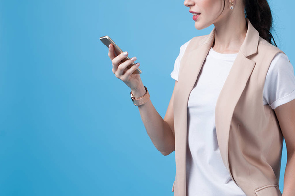 Beautiful successful young business woman uses phone on blue background. Anonymous business portrait - Foto, immagini
