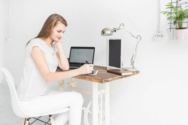 Young business woman working at home and draws on the tablet. Creative Scandinavian style workspace - Photo, Image