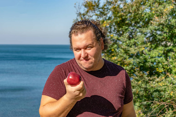 Hombre gordo divertido en el océano comiendo frutas
 - Foto, imagen